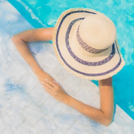 A woman with a sun hat in a pool.