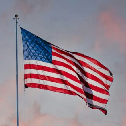 A raised flag of The United States of America waving in the wind.
