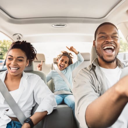 A happy African American family inside a car.