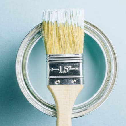 A paint brush resting on top of a paint can.