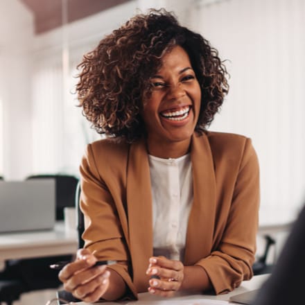 A smiling African American woman sitting at her desk.