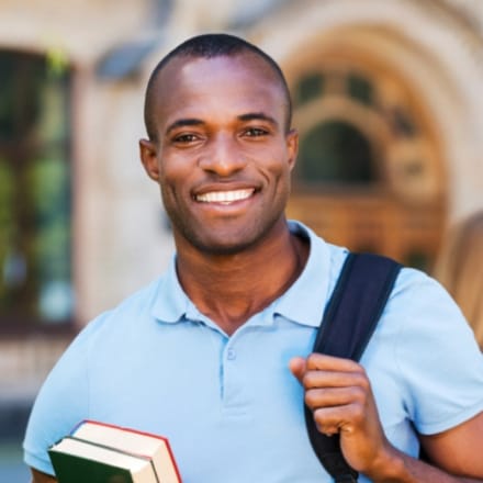 A young African American male student carrying books with a backpack.