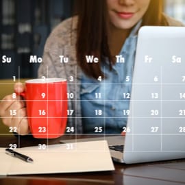 A woman drinking coffee at a desk with a transparent calendar in front.