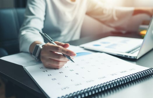 A person sitting at a desk with a calendar open.