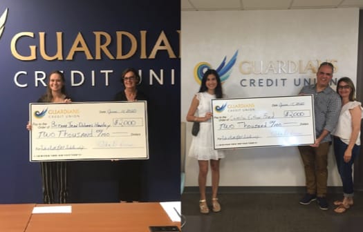 Two scholarship winners holding a human-sized check.