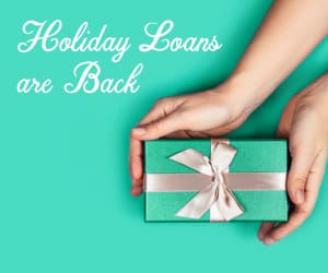 A hand holding a gift box. To the left, the words: holiday loans are back