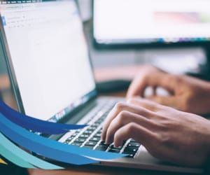 A side view of a person typing on a laptop.