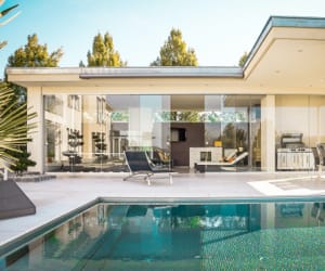 A living room view from the patio of a modern, one-story home.