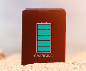 A battery bank standing upright in beach sand.