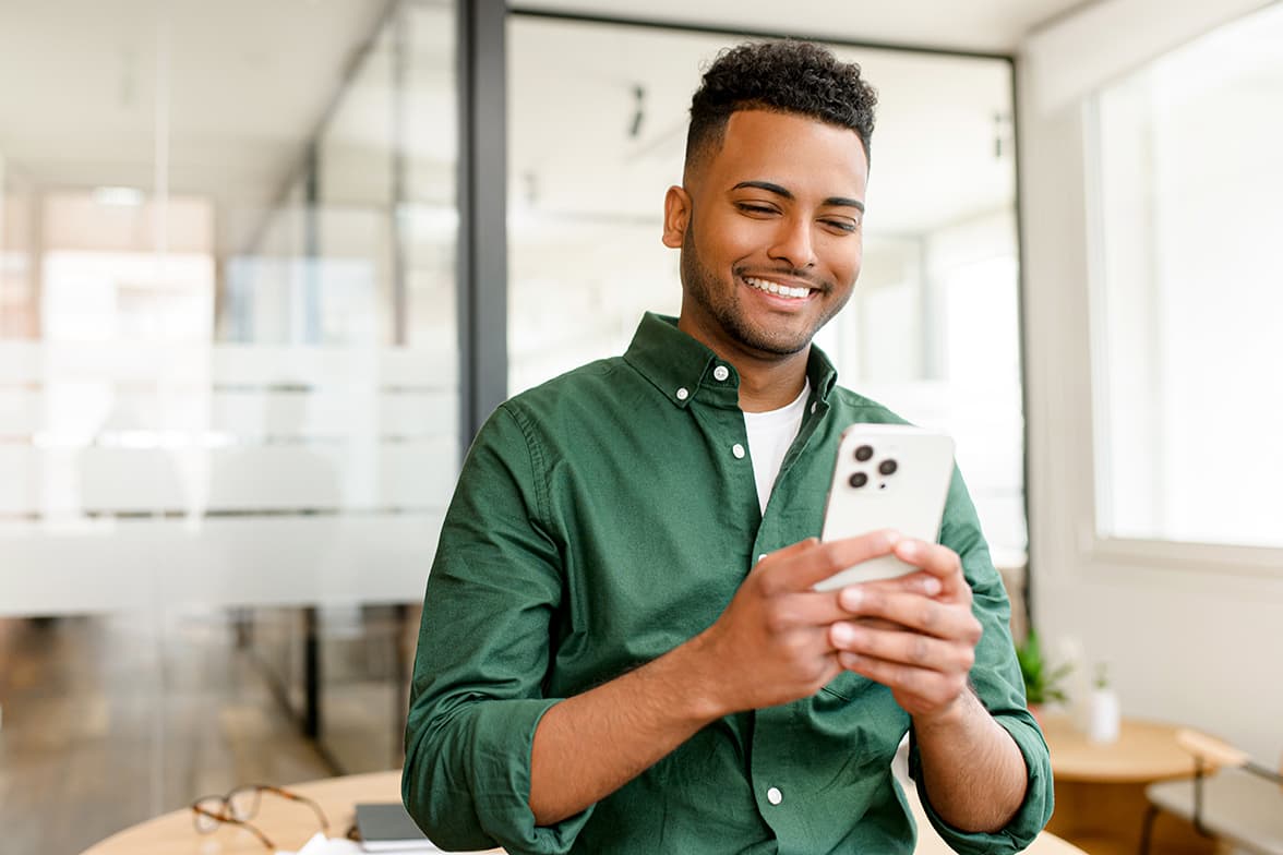 A young man smiling while holding a smart phone.