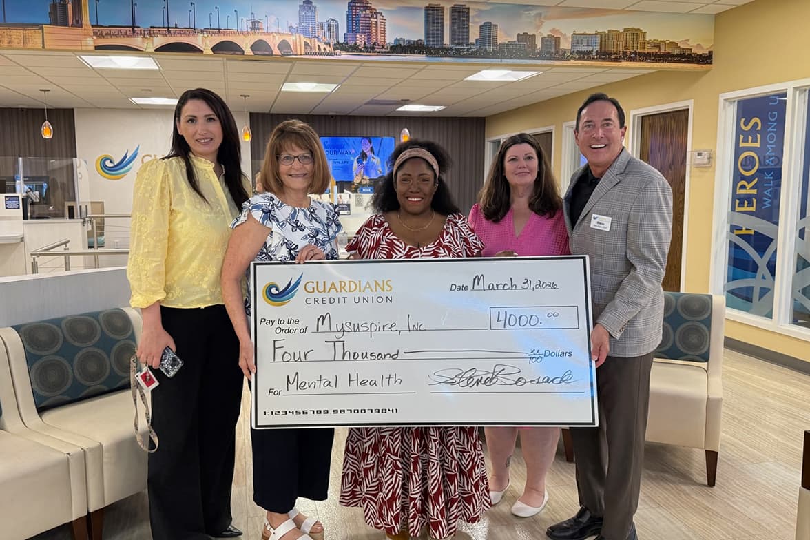 Guardians employees holding a giant check for Mental Health in the branch lobby.