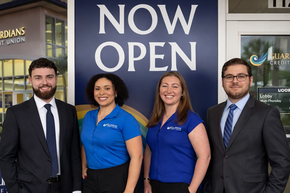Four Guardians employees standing in front of a branch entrance.