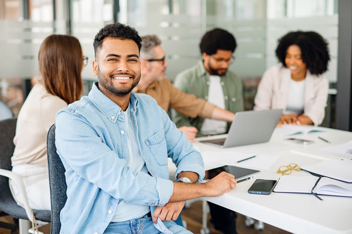 A young, male professional working at a desk with colleagues.