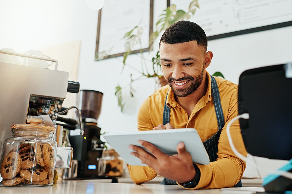 A barista using a tablet over a counter.