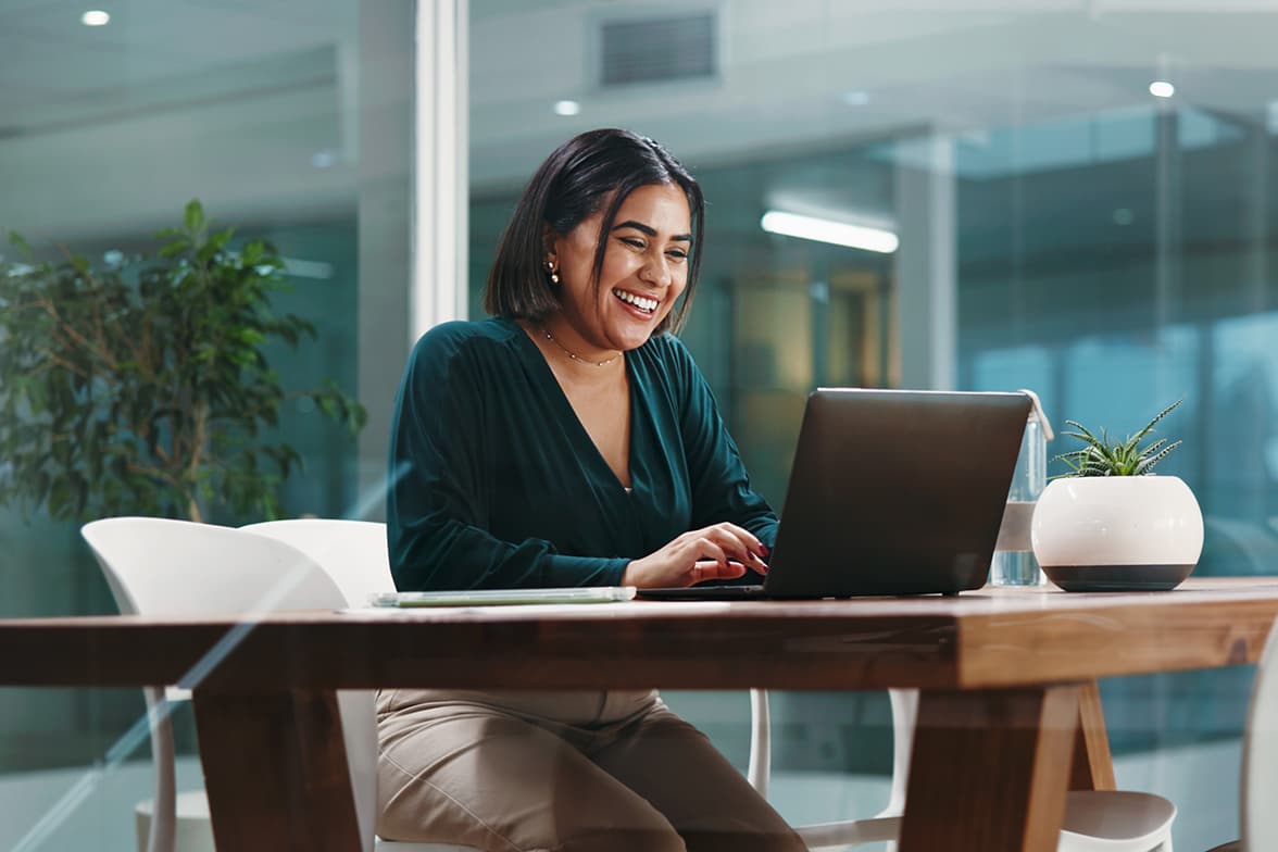 A professional woman sitting at a desk working on a laptop.