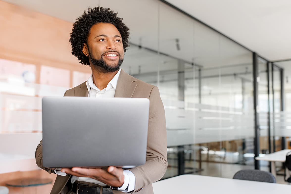 A young, professional man holding a laptop.