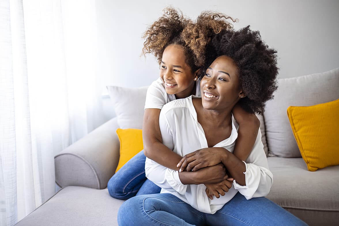 A young mother and daughter sitting on a couch.