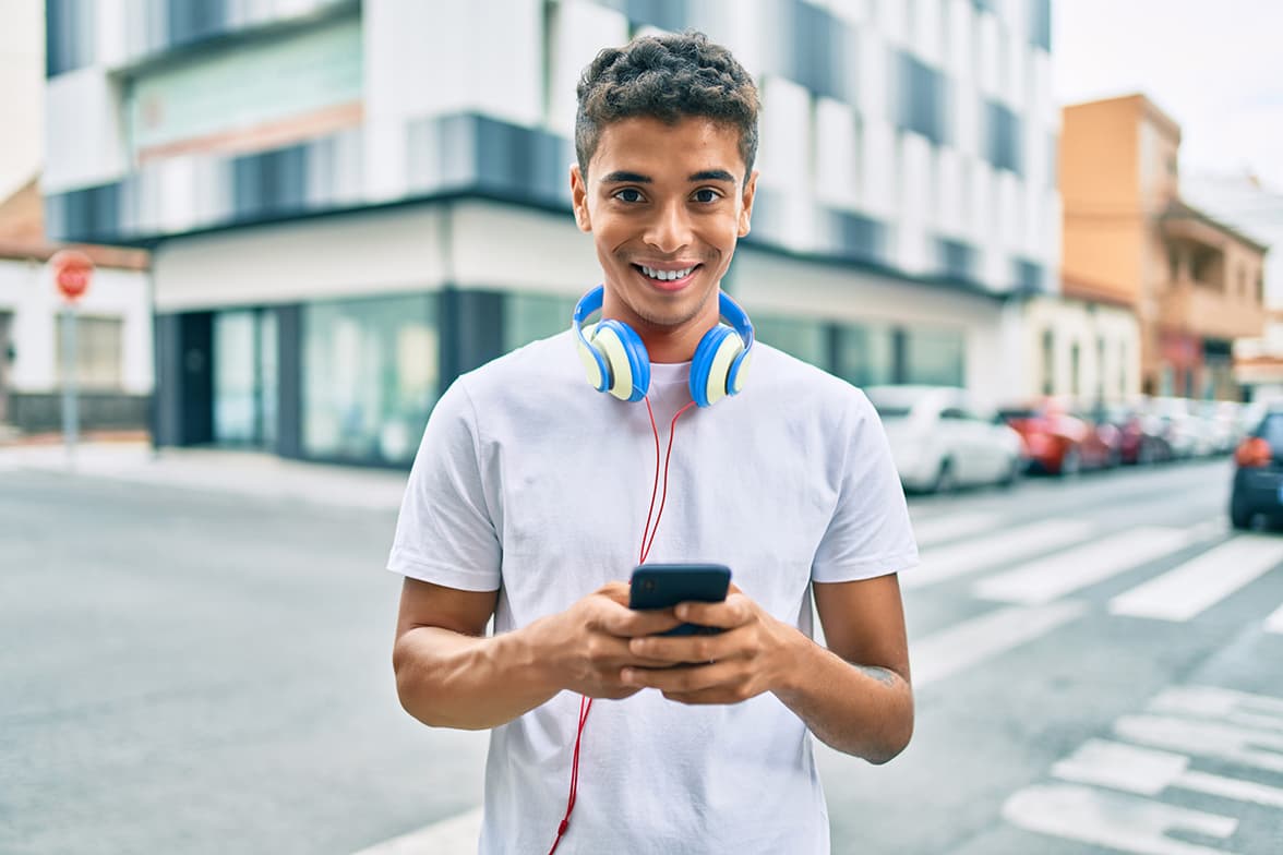 A young student wearing headphones and holding a smart phone.