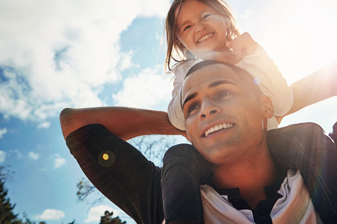 A young man carrying a toddler over his shoulders.