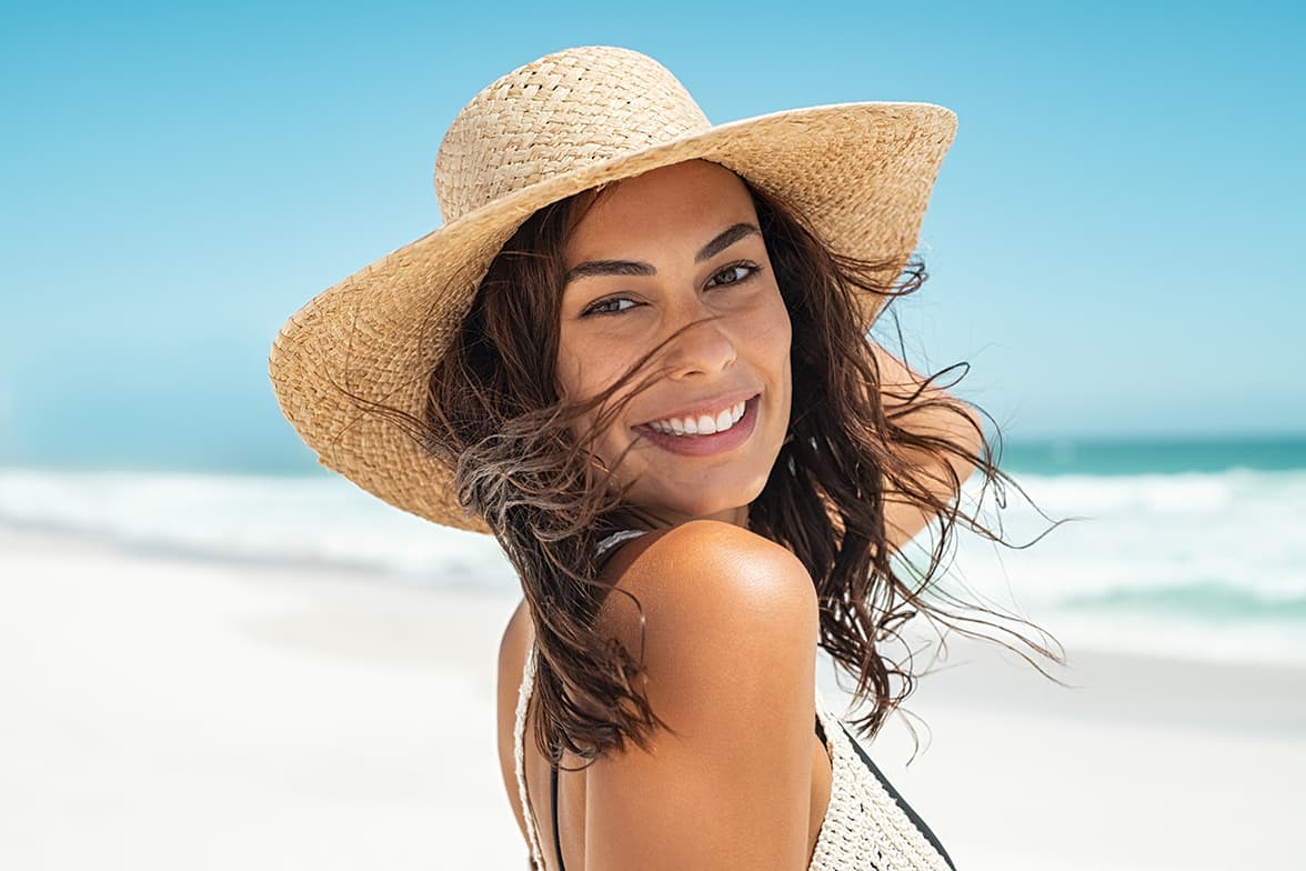 A woman wearing a straw hat at the beach.