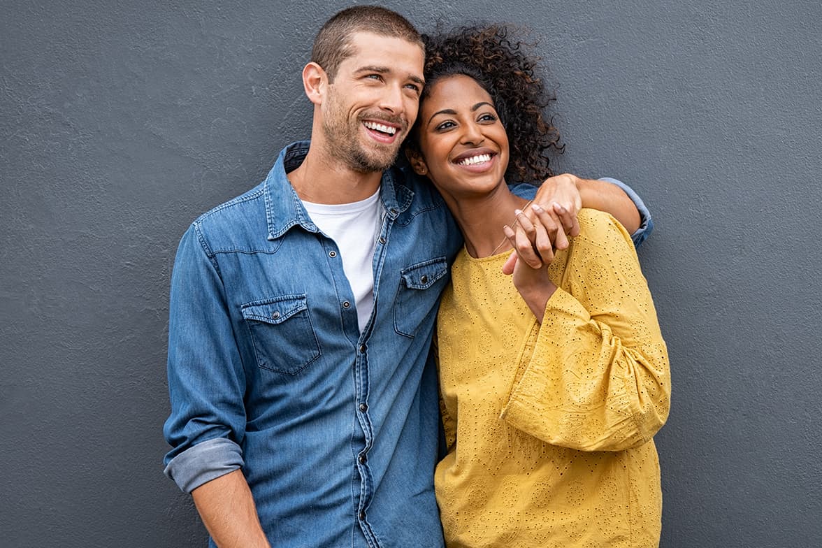 A young couple smiling and embracing eachother.