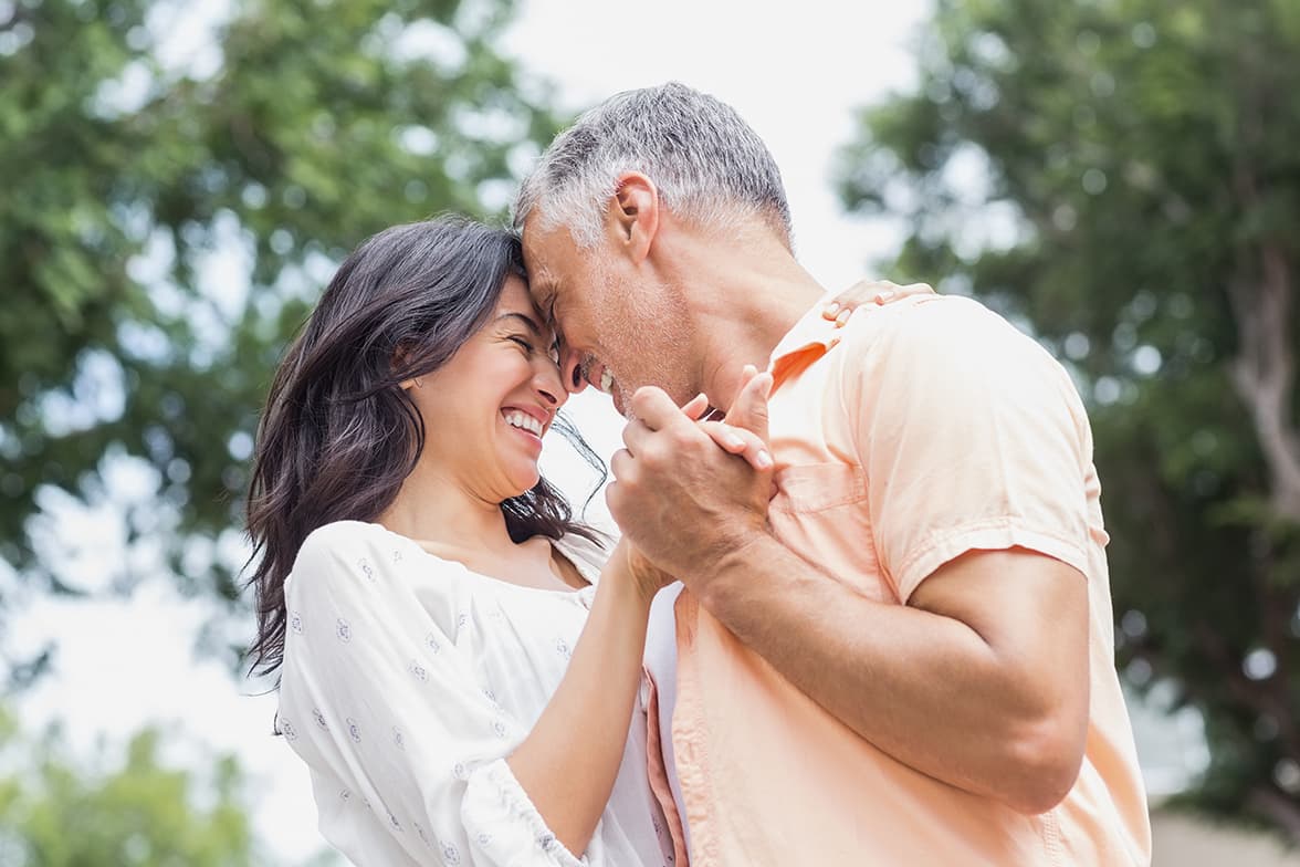 A middle-aged couple dancing outside.
