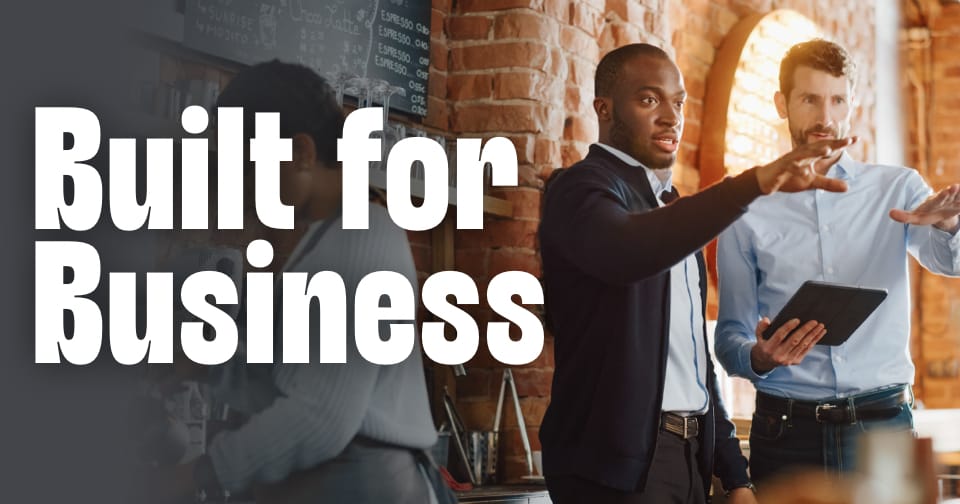 Two business professionals reviewing plans together inside a modern cafe setting. To the left, the words: built for business.