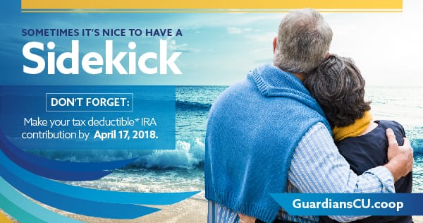An elderly couple embracing eachother on a beach looking out into the ocean.
