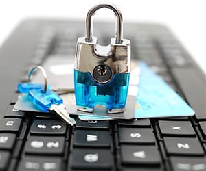 A blue lock and key on top of credit cards that are laying over a laptop